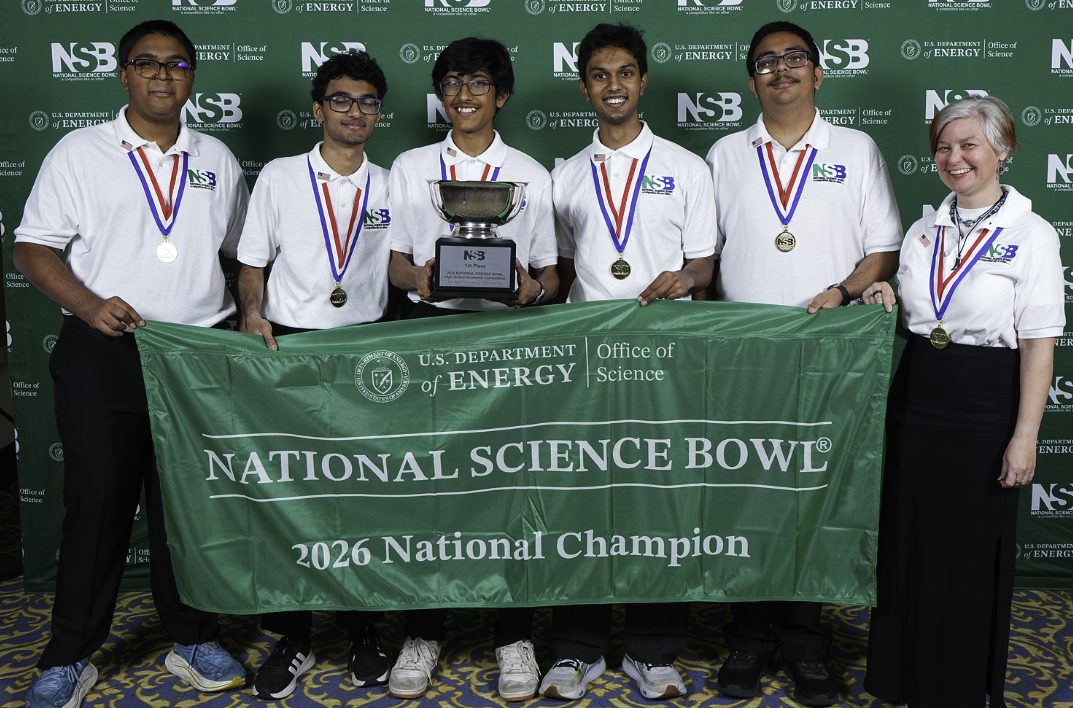 Five Science Bowl students and their coach holding a green banner reading National Science Bowl, 2026 National Champion