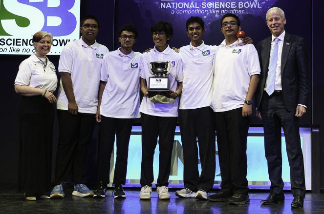 The team on stage at the National Science Bowl holding a trophy cup